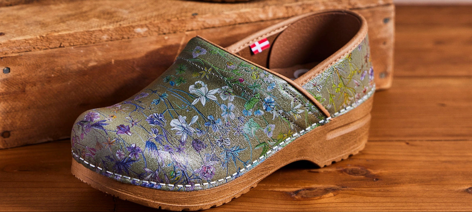 Floral green clog on wooden background - shop the Fuchsia in sage